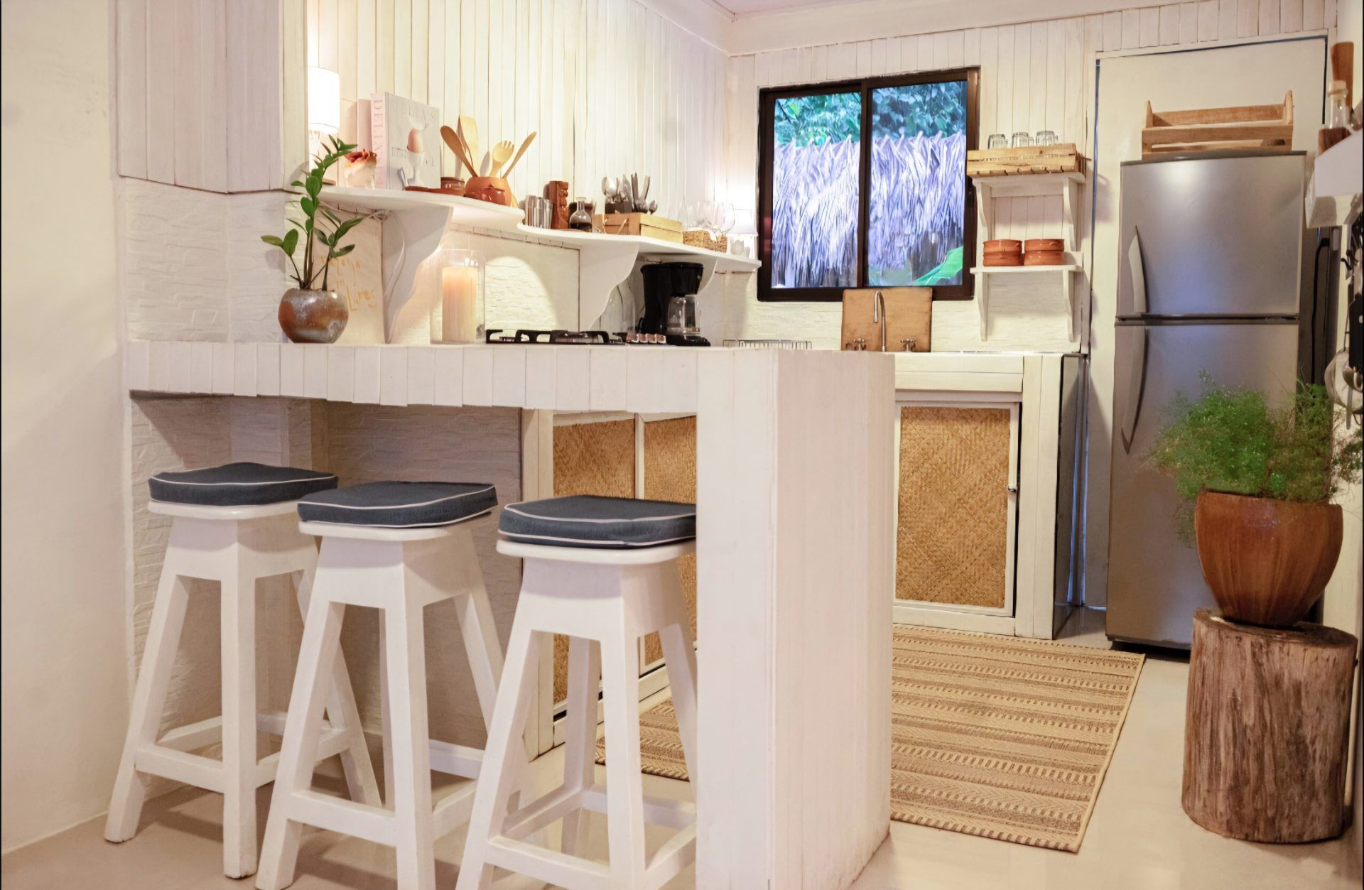 Kitchen with a breakfast bar and three stools, gas cooktop, coffee maker and stainless steel fridge