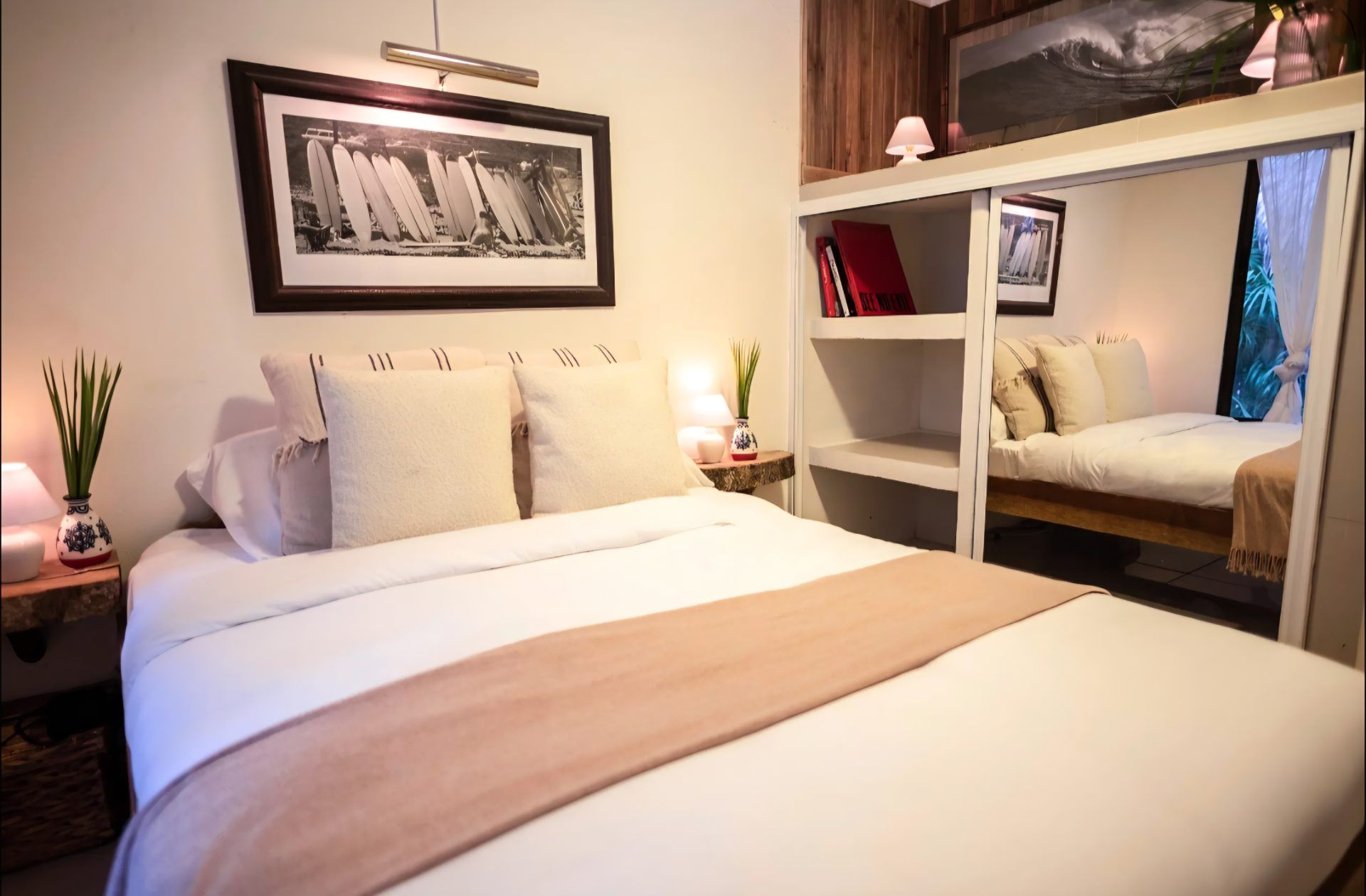 Bedroom with a double bed, bedside lamps, open shelving and mirrored closet doors
