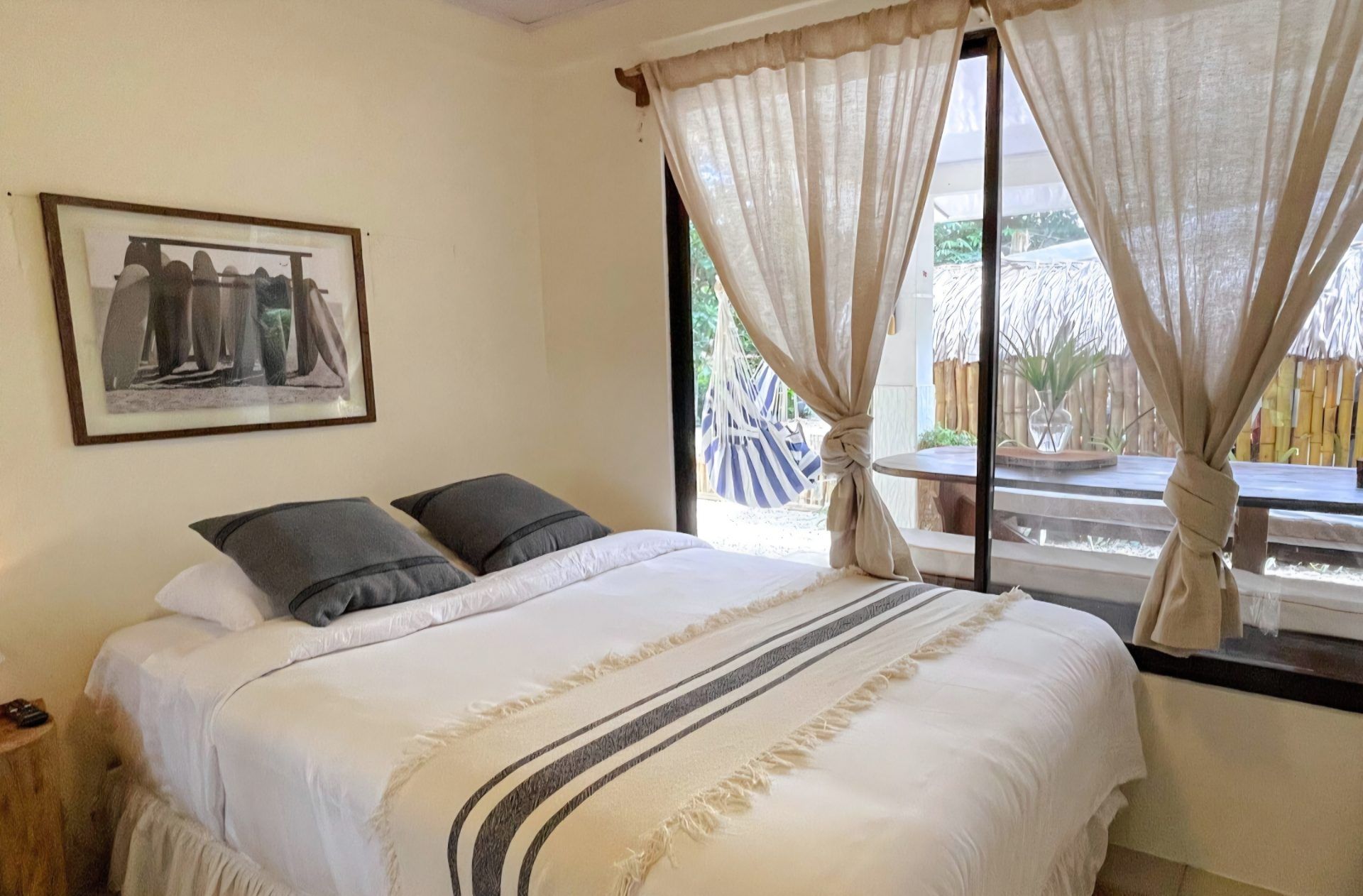 Bedroom with a queen bed and glass door opening onto a porch with a hammock and outdoor table
