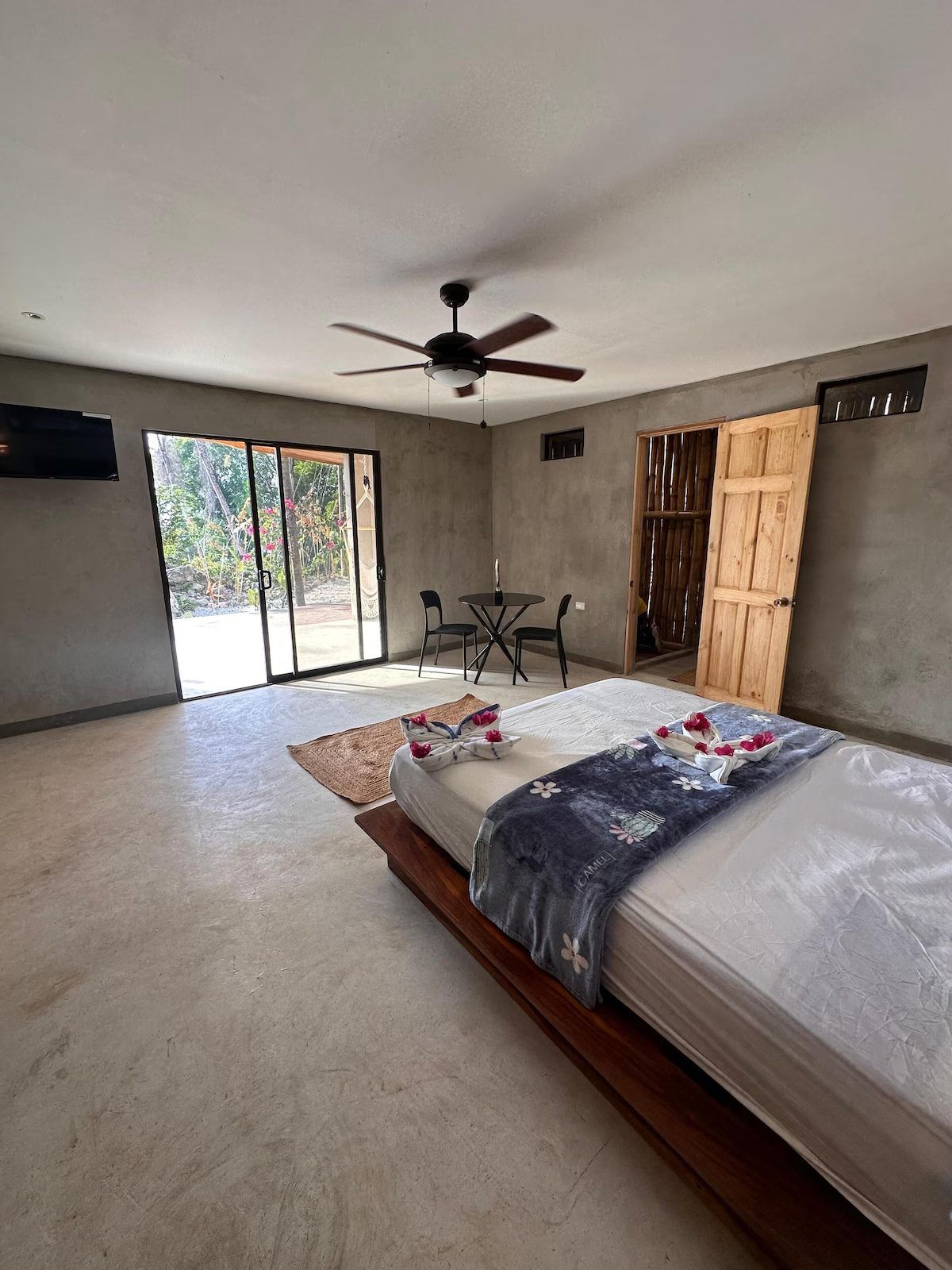 Bedroom with a queen bed, ceiling fan, wall TV and sliding glass doors opening onto a garden terrace