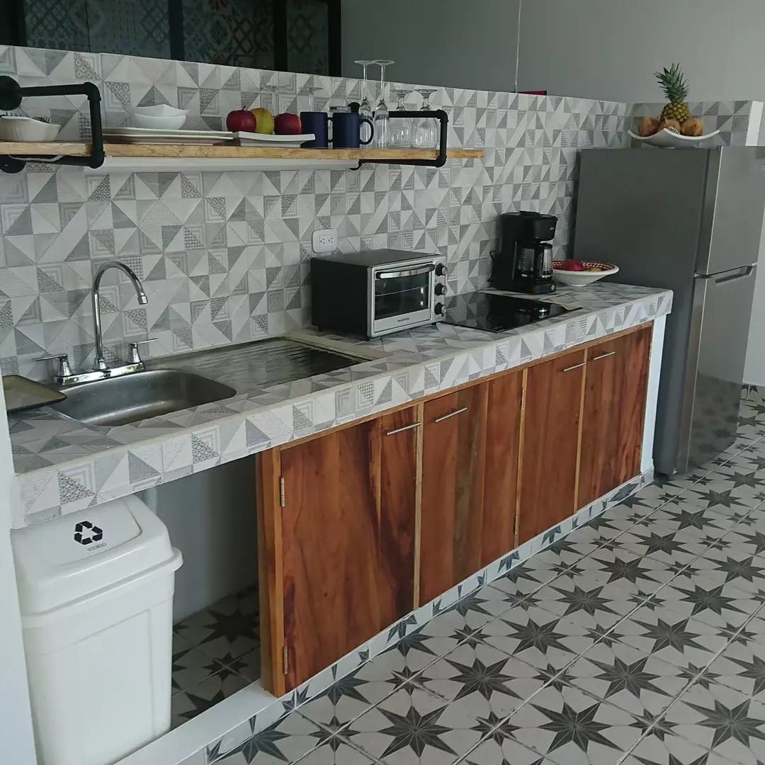 Kitchen counter with sink, induction cooktop, toaster oven, drip coffee maker and a fridge