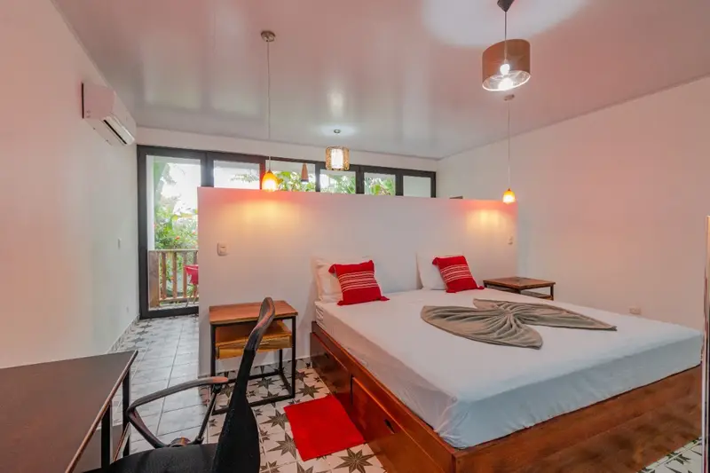 Bedroom with a queen bed, wall-mounted A/C and a desk with office chair, glass doors opening to a balcony