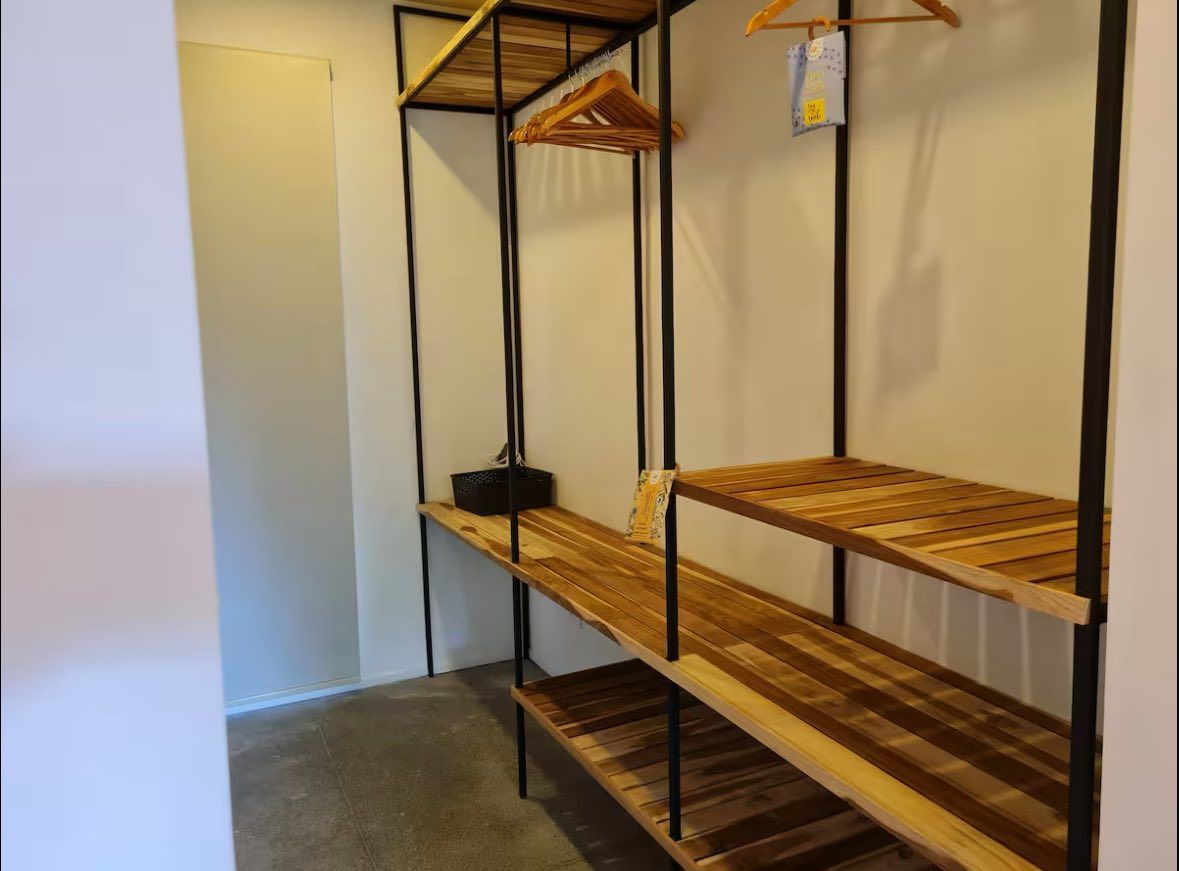 Walk-in closet with open wooden shelves and a hanging rail with hangers