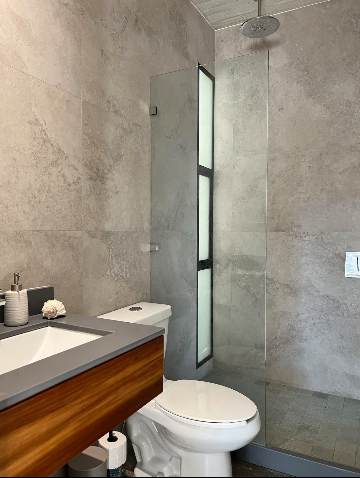 Bathroom with vanity sink, toilet and a glass-screened walk-in rain shower